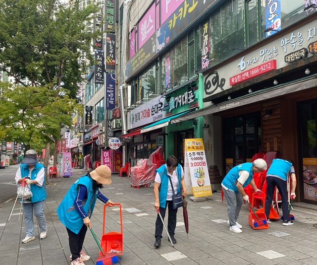 ▲ 신중동 자생단체원들과 동 직원들이 신중동 먹자거리의 무단투기 쓰레기를 수거하고 있다.