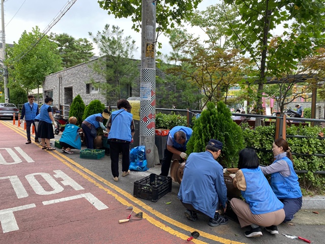 ▲ 중동 단체원들이 장말공원 일원에서 환경정화 활동과 꽃 묘를 식재하고 있다.