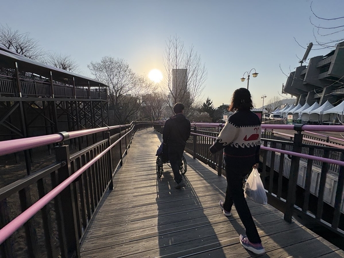 1-2. 휠체어 이용객이 무장애 데크로드를 이용해 이동하고 있다.jpg