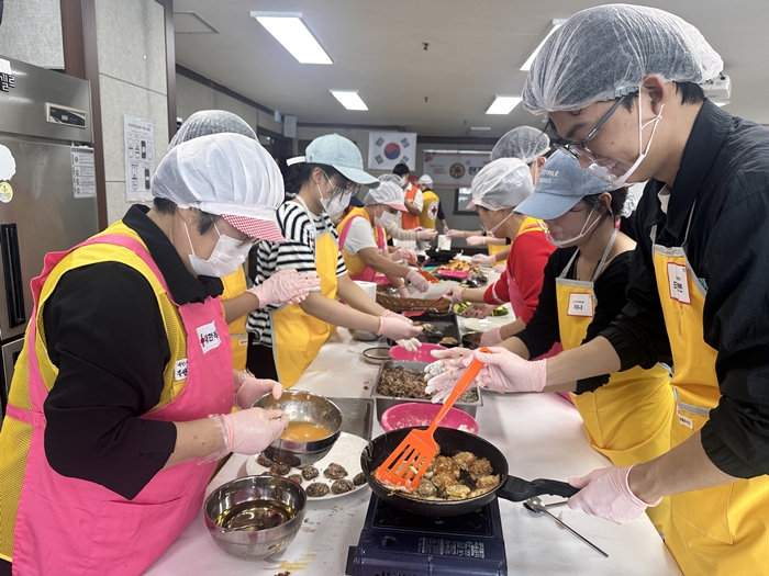 6-1. 한국인 봉사자와 외국인 유학생이 짝을 이뤄 함께 전을 부치고 있다.jpg